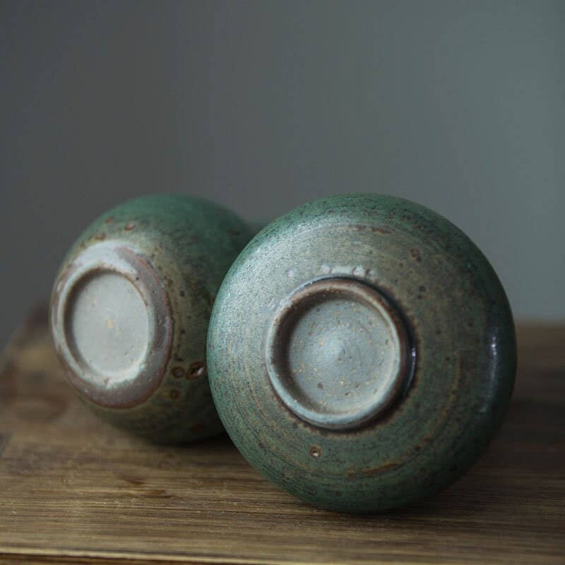 two green vases sitting on top of a wooden table