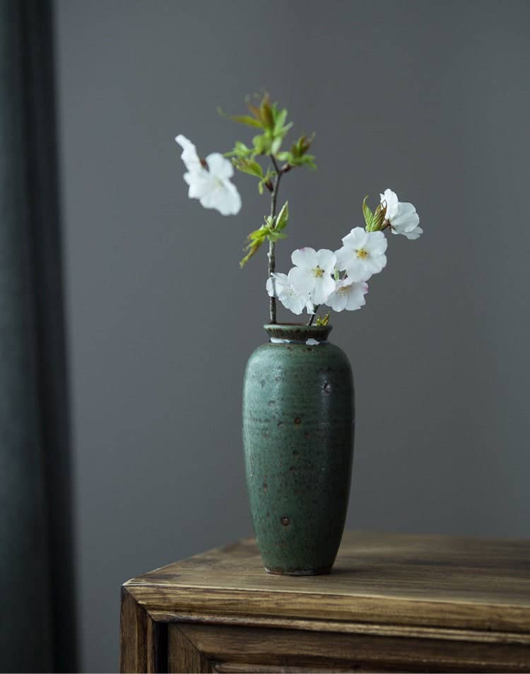 a green vase with white flowers in it