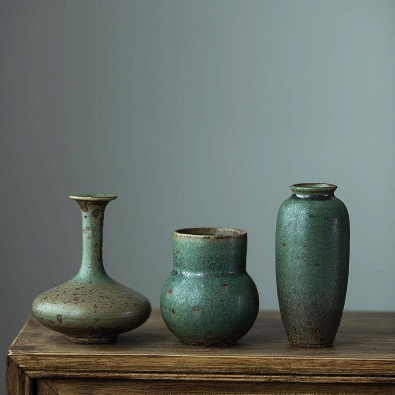 a group of three vases sitting on top of a wooden table