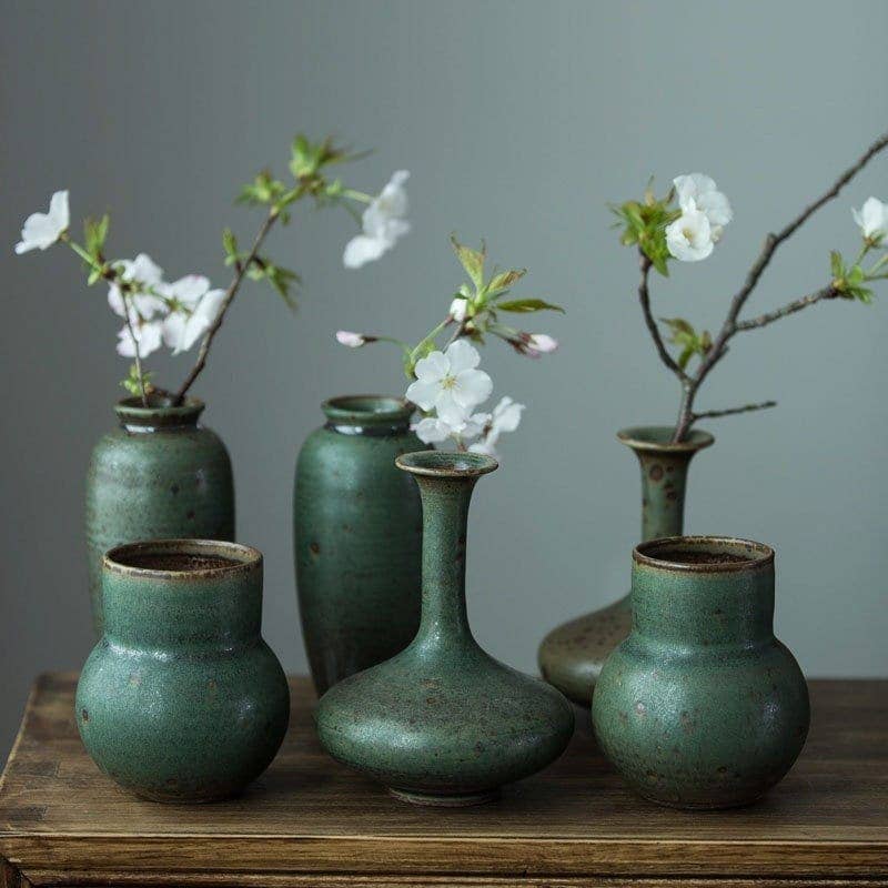 three green vases with white flowers in them